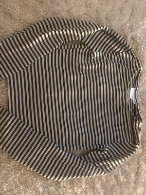 Randig långärmad topp från Gina Tricot - Snygg långärmad topp från Gina Tricot med svarta och vita ränder. Klassisk rak passform och rund halsringning. Perfekt att styla med jeans eller kjol för en cool vardagslook.