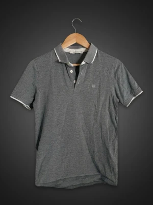 👕 Jack & Jones Premium pikétröja – Stilren & tidlös 👕 - Snygg grå pikétröja från Jack & Jones Premium med klassisk krage, knappslå och diskreta detaljer i vitt. Perfekt för både vardag, jobb och mer uppklädda tillfällen. Bekväm passform och lätt att matcha med jeans, chinos eller shorts.  ✔️ Jack & Jones Premium ✔️ Klassisk pikémodell ✔️ Stilren grå färg ✔️ Mjuk och bekväm kvalitet ✔️ Perfekt för vår, sommar och höst ✔️ Fint skick  Märke: Jack & Jones Premium Färg: Grå Modell: Pikétröja / Polo Shirt Skick: Mycket bra