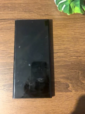 Samsung Galaxy S23 Ultra - Snygg svart Samsung Galaxy S23 Ultra med stor skärm och flera bakre kameror. Telefonen har en stilren, rektangulär design i matt svart finish och tydliga Samsung-logga på baksidan. Perfekt för dig som gillar modern teknik och vill ha en kraftfull smartphone. Den är helt ny, inga skador alls och den fungerar perfekt. Priset kan diskuteras!