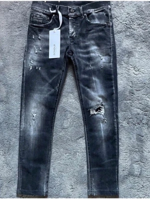 Svarta slitna jeans från Dondup - 90cm längd 39cm bredd vid midjan Köpte för 4000kr på united. Säljer ett par svarta jeans från Dondup med slitningar och hål för en riktigt edgy look. Jeansen har skinny fit, klassisk femficksmodell och cool tvätt med ljusa partier. Perfekta för dig som gillar streetstyle och vill sticka ut.