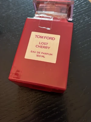 Tom Ford version Lost Cherry EdP 100ml - Tom Ford version Lost Cherry Eau de Parfum i en snygg röd glasflaska med transparent röd kork. Flaskan rymmer 100 ml och har en modern, fyrkantig design. Oanvänd!