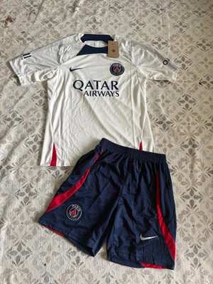 PSG matchställ Nike vit/blå - Psg fotbollsset i storlek S. Shortsen har fickor med dragkedjor. Helt nya och oanvända, Hör gärna av vid frågor!