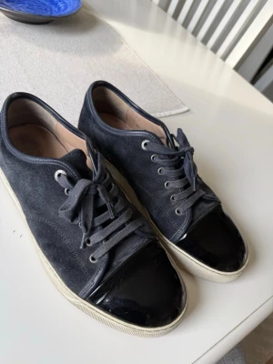 Lanvins - Snygga lanvins med ovandel i mocka och en glansig, lackad tå. Skorna har vita sulor och mörkblå skosnören. Perfekta för dig som gillar en stilren men ändå unik look. Passar till det mesta och ger en cool touch till outfiten.