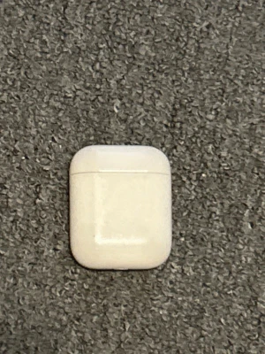 Apple AirPods med laddningsetui - Säljer ett par vita Apple AirPods med det klassiska laddningsetuiet. Trådlösa in-ear hörlurar i stilren design, perfekt för musik, samtal och poddar. Smidig förvaring och laddning i det kompakta etuiet. Passar till alla Apple-enheter med Bluetooth.