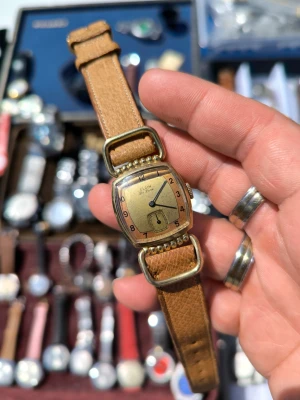Elgin de lux mekaniks ( ww2 i 18k PT ) Läs Info - Retro klocka från Elgin med fyrkantig guldfärgad boett och brunt läderarmband. Urtavlan är guldfärgad med svarta siffror och små sekunder vid 6-positionen. Klassisk och unik design som sticker ut på handleden. Info : kocka är i fungerar skick . Det är in Vintage retro klocka förvänta inter kommer med någon användning repor : den klocka skick repro är bra ingen man märker till för sin older  både för men och kvinnor 