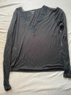 Svart långärmad topp med spets - Svart långärmad topp från & Other Stories med djup v-ringning dekorerad med spetsdetaljer. Tillverkad i mjukt material som känns skönt mot huden. Perfekt för att lyfta en enkel outfit med en elegant touch. Det är ingen fläck det är lappen från insidan! Tröjan är liten i storleken👍