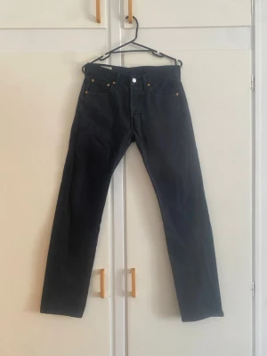 Levi's Premium svarta jeans, storlek W29 L32 - Snygga svarta jeans med klassisk rak passform och fem fickor. Jeansen har knappgylf och detaljer i kopparfärg på nitarna. Tillverkade i denim, perfekta för en avslappnad och stilren look.