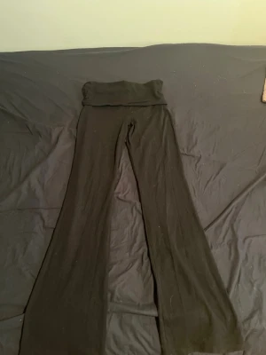 Svarta utsvängda leggings - Snygga svarta leggings med utsvängda ben och en midja som går och vika ner som blir lågmidjad. Perfekta för en trendig och bekväm stil. Mjukt och stretchigt material som sitter skönt hela dagen.