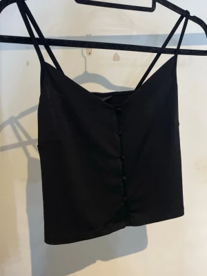 Linne med knappar - Ett svart linne med knappar från Gina Tricot, storlek S.