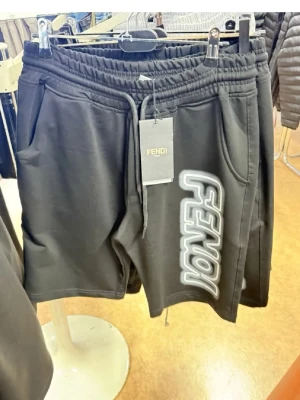 Svarta shorts med tryck från Fendi - Svarta shorts från Fendi med resårmidja och snörning. Stora fickor på sidorna och ett iögonfallande vitt och grått tryck längs ena benet. Perfekta för en avslappnad och trendig look.