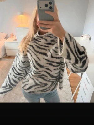 Zebramönstrad stickad tröja - Säljer en fluffig stickad tröja med zebramönster i svart och vitt. Tröjan har hög krage och vida ärmar för en avslappnad och trendig look. Perfekt att styla med jeans för en cool outfit. Köpt på Vinted men för stor för mig tyvärr, storlek m men passar även S❤️