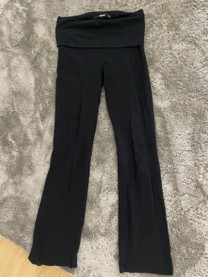 Svarta bootcut yogapants från bikbok - Svarta yogapants med bootcut-modell från bikbok. Hög midja med bred linning som kan vikas ner för en avslappnad look. Mjukt och stretchigt material som sitter skönt på kroppen. 
