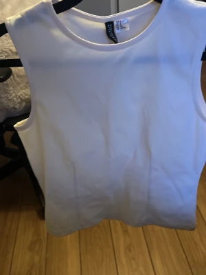 Vit ärmlös linnetopp från Gina Tricot - Snygg och stilren vit linnetopp från Gina Tricot. Toppen är ärmlös med rund halsringning och har en enkel, rak passform. Perfekt att matcha med jeans eller kjol för en fräsch look.