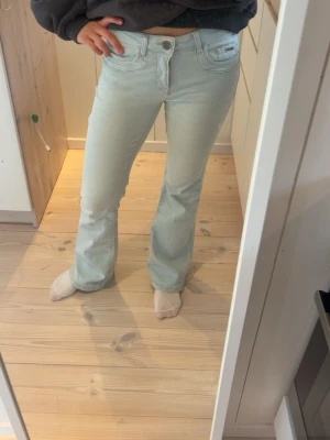 Ljusblå bootcut jeans - Snygga ljusblå bootcut jeans med klassisk femficksdesign och vita sömmar. Jeansen har en något utsvängd passform nertill och normalhög midja. Perfekta för en avslappnad och trendig look.