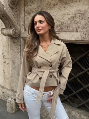 Kort beige trenchcoat med knyt - Snygg trendig beige trenchcoat från Gina Tricot med dubbelknäppning och knytskärp i midjan. Modellen är kortare och har en stilren look. Perfekt tunnare jacka till vardags🥰