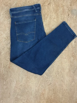 Blåa skinny jeans med bakficka - Ett par blåa skinny jeans med klassisk bakficka och ljus kontrastsöm. Jeansen har hög midja och raka ben, tillverkade i mjukt denim-material. Perfekta för dig som gillar en enkel och stilren look.