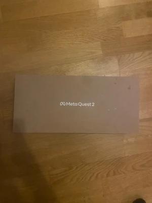 Meta Quest 2 VR-headset med kontroller - Meta Quest 2 VR-headset i vit plast med justerbart band och två matchande handkontroller. Allt ligger i originalförpackning. Perfekt för dig som vill uppleva VR-spel och appar på en ny nivå. En kontroll har lite stickdrift men fixas snabbt och lätt!