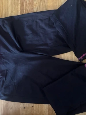 Svarta leggings - Svarta leggings med stretchigt tyg och rosa detaljer.  Klassisk, tight passform som funkar till många olika stilar. Finns ingen lapp men strl L. 