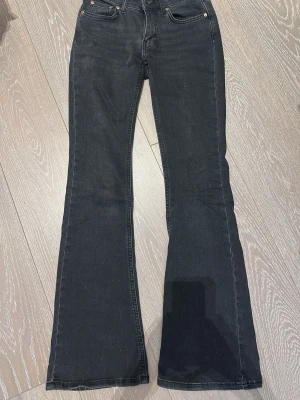 Svarta bootcut jeans med hög midja - Snygga svarta bootcut jeans med hög midja och klassiska fem fickor. Jeansen har utsvängda ben och är tillverkade i ett mjukt denimtyg. Perfekta för dig som gillar en retroinspirerad look.