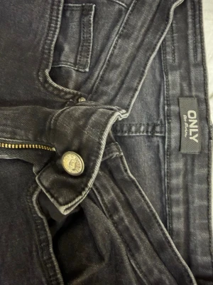 Svarta raka jeans från ONLY - Snygga svarta jeans från ONLY med raka ben och klassisk femficksdesign. Jeansen har dragkedjegylf och knapp framtill. Perfekta till en avslappnad stil och lätta att matcha med olika outfits.