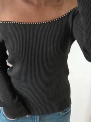 cool off shoulder top - Snygg mörkgrå offshoulder topp med ribbad struktur och små pärldetaljer längs urringningen. Figurnära passform och långa ärmar. Perfekt för dig som gillar en trendig och stilren look.