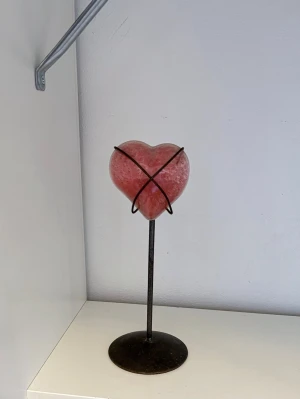 Rosa hjärtformad ljushållare i glas - Unik ljushållare med hjärta i rosa glas och svart metallställning. Hjärtat har bubblig struktur och hålls på plats av metalltrådar. Perfekt som dekoration eller för värmeljus.