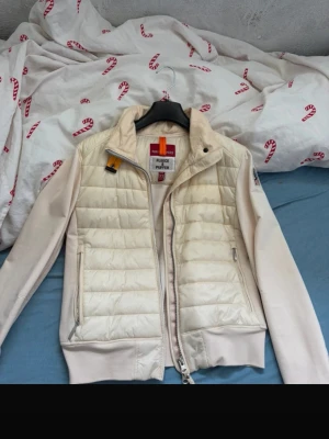 Vit dunjacka från Parajumpers - Snygg och stilren vit dunjacka från Parajumpers med quiltat mönster och dragkedja framtill. Västen har ribbade muddar, två fickor med dragkedja och klassisk PJS-logga på axeln. Perfekt för lager-på-lager och streetstyle.