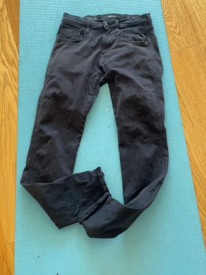 Replay jeans - Säljer ett par svarta jeans från Replay med klassisk femficksdesign och smal passform. Jeansen har dragkedjegylf och diskreta detaljer på bakfickorna. Perfekta för en stilren och avslappnad look.