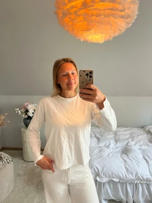 Vit pyjamas med långärmad tröja - Mysig vit pyjamas med långärmad tröja och matchande byxor. Setet har en avslappnad passform och är perfekt för hemmakvällar. Materialet ser ut att vara mjukt och bekvämt, perfekt för att chilla eller sova i.