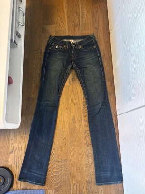 Mörkblå jeans från True Religion - Ikoniska True Religion jeans i mörk tvätt med klassiska kontrastsömmar och signaturdetaljer 🤍 Stretchig och smickrande modell som formar fint och ger en lång silhuett. Väldigt snygga både uppklädda med klackar eller mer casual med sneakers.  Storlek: 24 Färg: Mörkblå denim Skick: Fint använt skick