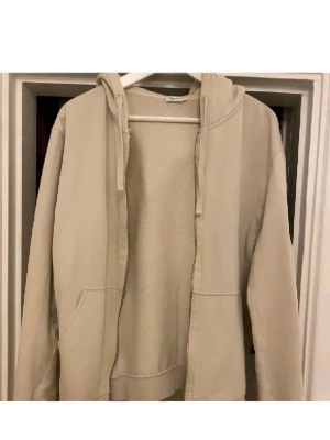 Beige hoodie från Filippa K - Säljer en stilren beige hoodie från Filippa K i mjuk bomull. Tröjan har dragkedja framtill, huva med snören och två fickor. Perfekt för en avslappnad look och enkel att matcha med det mesta. Nypris 1999kr från NK Stockholm 