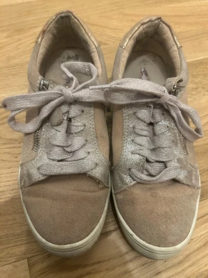 Rosa sneakers med glitterdetaljer - Snygga gammalrosa sneakers från  med glittriga detaljer och breda, skimrande skosnören. Skorna har dragkedja på sidan och vit sula. Ovandelen är i mockaliknande material. Perfekta för en trendig vardagslook. Från Hush Puppies. 
