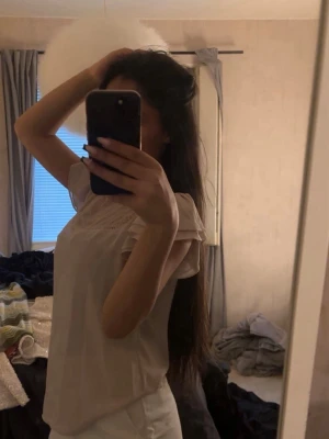 Ljusbeige blus med spetsdetalj - Söt ljusbeige blus med korta ärmar och fin spets upptill vid axlar och halsringning. Blusen har en avslappnad passform och är perfekt för en stilren look. Materialet känns mjukt och lätt, vilket gör den skön att bära.