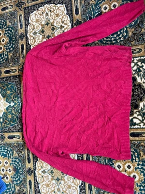Mörkrosa stickad tröja från GANT - Säljer en mörkrosa stickad tröja från GANT med rund halsringning och diskret broderad logga på bröstet. Tröjan har lång ärm och ribbade muddar vid ärmslut och nederkant. Perfekt för dig som gillar klassisk och enkel stil.