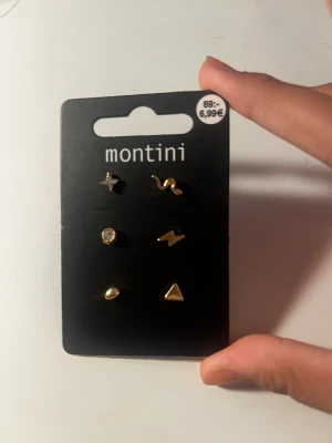 Två set örhängen Montini & Ur&Penn - Säljer två set örhängen. Montini-setet har sex olika guldiga örhängen i olika former som stjärna, blixt, triangel och pärla. Ur&Penn-setet innehåller sex små örhängen med guldfärgade stenar. Perfekt för dig som gillar att mixa och matcha.