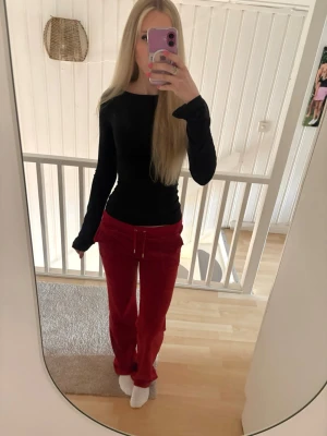 Röda juicybyxor med fickor - Snygga röda mjukisbyxor från juicy couture, mjuk velour med raka ben och bred resår i midjan. Byxorna har två bakfickor med lock och silverfärgade knappar. Perfekta för en chill och avslappnad stil.