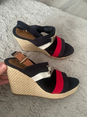 Tommy Hilfiger kilklackade sandaler - Jättefina klackar från Tommy hilfiger i storlek 38. Använt klackarna 1 gång men var inte direkt min stil så därav säljer jag dem. Köpta för 1799 och är i ny skick. Lite damm på bilderna men de gör jag rent och fint innan paketet skickas! 😇🥰 