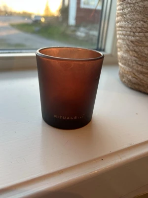 Brun ljuslykta från Rituals - Snygg brun ljuslykta i frostat glas från Rituals. Citatet 'One beautiful fragrance can create many beautiful memories' syns på ena sidan. Perfekt som dekoration i hemmet.