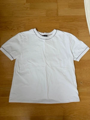 Vit t-shirt med detaljer  - Vit t-shirt från Zara med korta ärmar och detaljer runt halsen och ärmarna. T-shirten är i storlek M.
