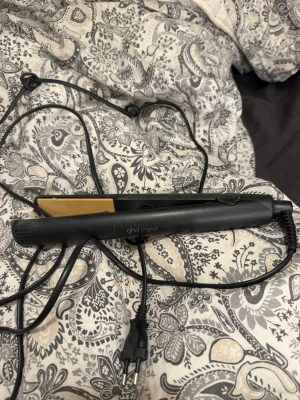 ghd original plattång svart - Säljer en svart ghd original plattång med guldfärgade keramiska plattor. Perfekt för att styla håret rakt eller skapa lockar. Plattången har en smidig design och lång sladd för enkel användning.