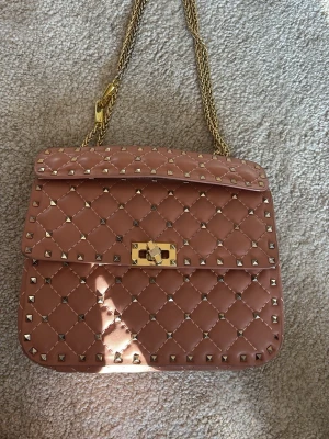 Rosa Valentino Rockstud handväska - Säljer en rosa quiltad handväska från Valentino med guldiga nitar och kedjerem. Jag köpte väskan här på Plick och den saknar även en nit.