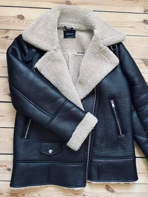 Shearlingjacka - En någorlunda oversize-passande jacka i faux läder med mjukt beigefärgat foder som passar perfekt till hösten och vintern. Den har ett spänne vid halsen (se bild 4), men går också att bära öppen (se bild 1). Jackan har inga synliga defekter. Kontakta mig vid behov av mer information eller bilder, och förhandling är självklart möjlig vid pris!