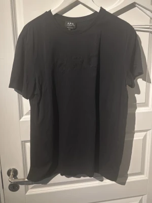 Svart t-shirt från A.P.C. - Säljer en svart t-shirt från A.P.C. med diskret logga framtill. Klassisk rund halsringning och korta ärmar. Tillverkad i mjuk bomull för en skön känsla och enkel stil.