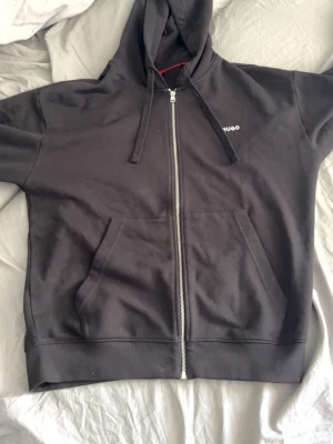Svart zip hoodie från Hugo - Säljer en zip hoodie från hugo, köpt i januari och bara stått i min garderob har använt den max 2 gånger. Gillar inte hur den sitter på mig därav säljer jag :)