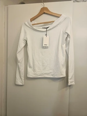Vit långärmad topp från BikBok - Snygg vit långärmad topp från BikBok med bred, något offshoulder ringning. Tillverkad i mjuk bomullsmix som känns skön mot huden. Perfekt att styla med jeans eller kjol för en clean look.
