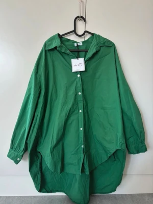 Grön oversized skjorta från Mix by Heart, Ny med prislapp - Säljer denna sjukt snygga skjorta/tunika (perfekt över ett par skinnleggings nu i vår) alternativt som kort klänning på sommaren. OneSize.  ❌Finns en fläck på som var där när jag köpte den (se sista bilden). Går säkert att lätt få bort i tvätten men eftersom klänningen inte föll mig i smaken men jag missade datumet för retur så har jag inte velat ge mig på att ta bort fläcken. Annars nyskick!!❌