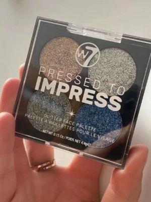 W7 Pressed to Impress ögonskuggspalett - Glittrig ögonskuggspalett från W7 med fyra intensiva nyanser: guld, silver, blå och mörkgrå. Paletten har en fyrkantig plastförpackning med genomskinligt lock och är perfekt för dig som vill ha extra shimmer till din look.