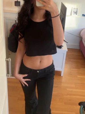 Svart croppad topp - En enkel och stilren svart croppad topp med rund halsringning och korta ärmar. Perfekt att matcha med höga jeans eller kjol för en trendig look.