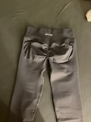DFYNE Seamless Scrunch Leggings - Mörkgrå - Storlek XS - Beskrivning: Säljer mina mörkgrå (dark grey/charcoal) DFYNE seamless leggings. De är i storlek Extra Small (XS) och har den perfekta passformen för gymmet! Dessa tights har den kända scrunch butt-detaljen som ger en jättefin form. Materialet är squat-proof, stretchigt och sitter som en smäck tack vare den höga midjan som inte rullar ner. De är i toppskick och säljes bara för att jag har för många färger av samma modell. Passa på att fynda ett par riktiga favoriter! • Märke: DFYNE • Färg: Mörkgrå