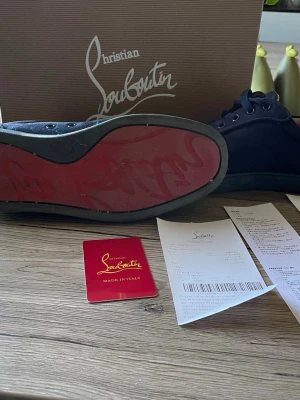 Christian Louboutin svarta sneakers - Snygga Christian Louboutin med den ikoniska röda sulan. De är använda men mockan är fortfarande bra . Dom är lite slitna men inte så, man tänker inte på det.